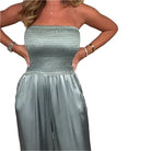 Elegant woman wearing the Grace - Wide Leg Jumpsuit, showcasing a strapless top and luxurious satin finish.